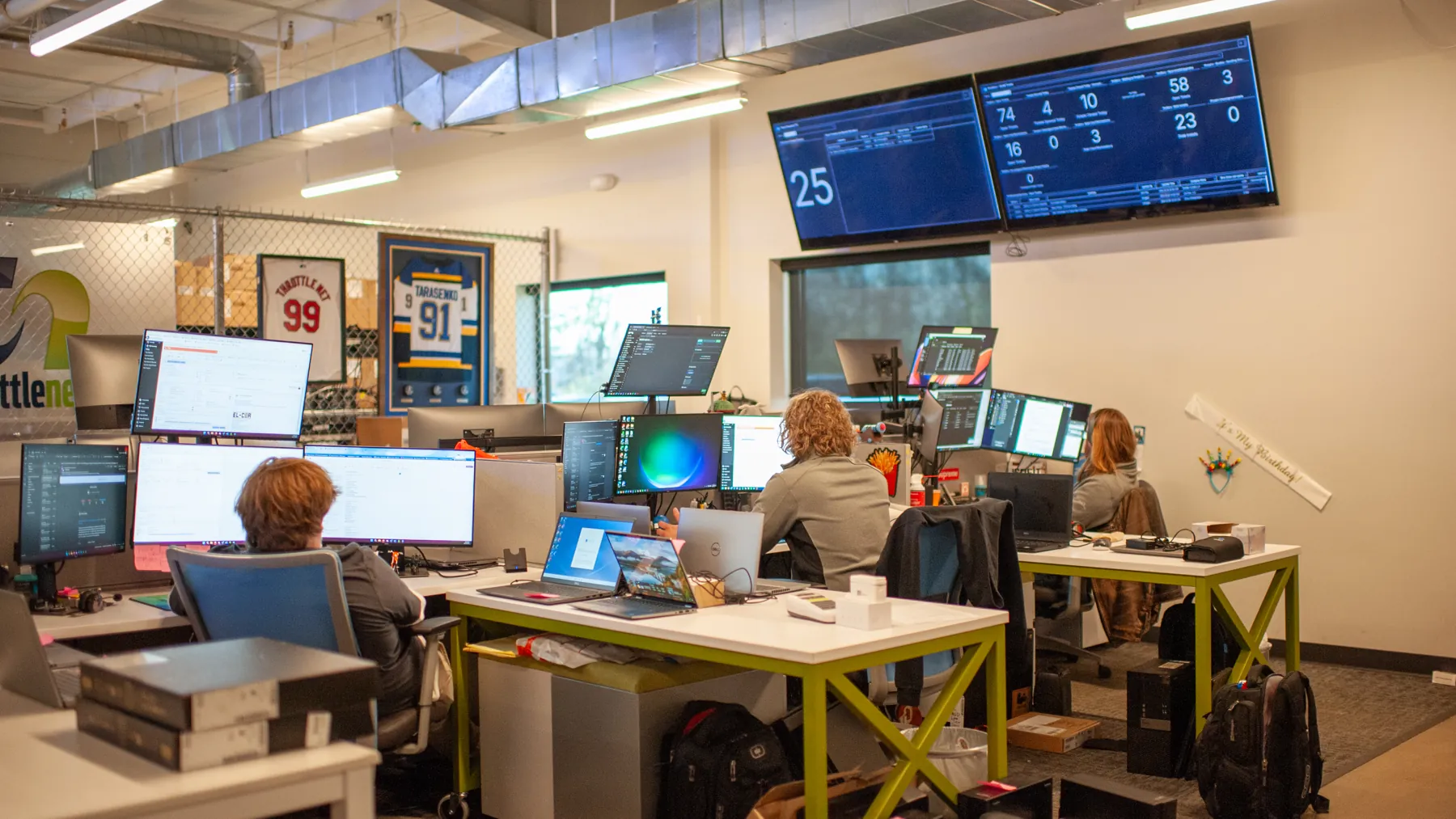 ThrottleNet operations floor: technicians at monitored desks under live service dashboards